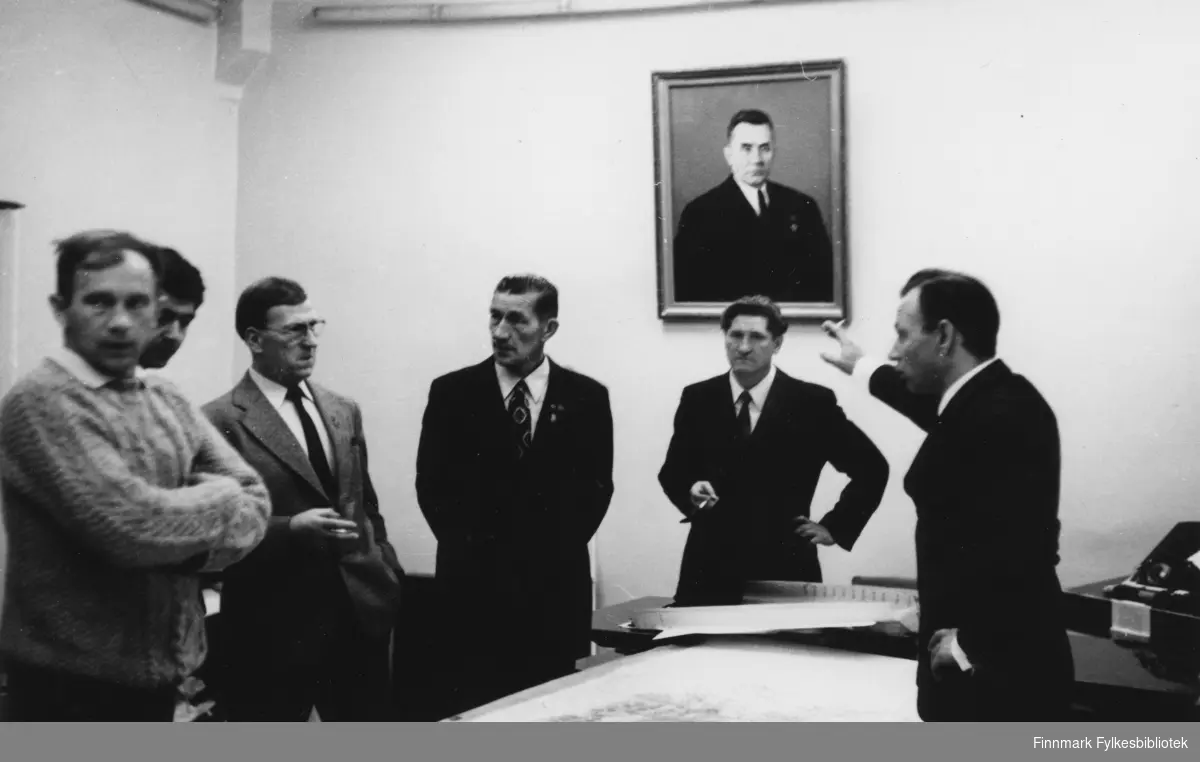Bilde fra en tur i Nikel i forbindelse med gruve/fagforeningsutveksling i Nikel, Russland på 1970-tallet. Fra venstre: Martin Seljemo, Simon Tivilov, Gunnar Antonsen, Gunnar Bakkeslett, og to ukjente russere. De står rundt et bord hvor det ligger kart på. På veggen henger et fotografi