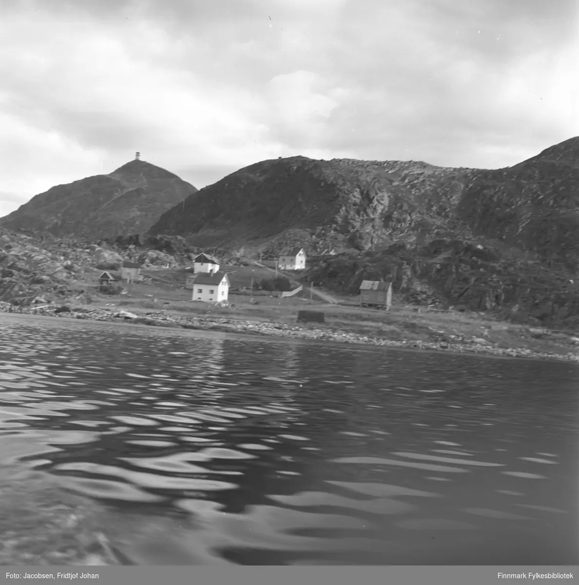 Bildet er tatt fra en båt mot Leirvika som ligger rett vest for Rypefjord. Fem boliger og et naust står på området. Veien fra Leivikhøgda/Rv 94 ses midt på bildet. Fjellet Tyven med masta under bygging ligger til venstre på bildet. Sjøen er blikkstille og det er overskyet.