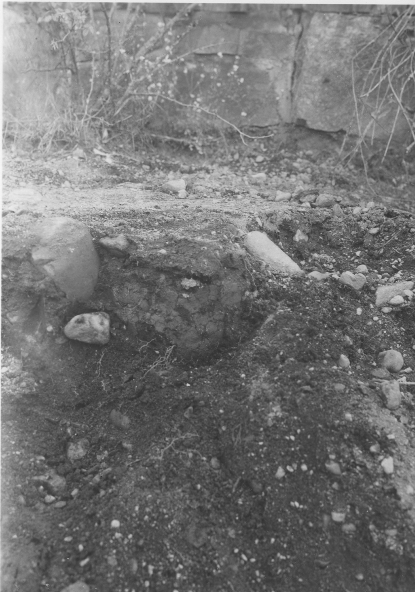 Trollhättan, Gärdhem, Fyndplats E fr. S. Urnan synes mellan stenarna. I bakgrunden stenfoten till Norlins stuga.