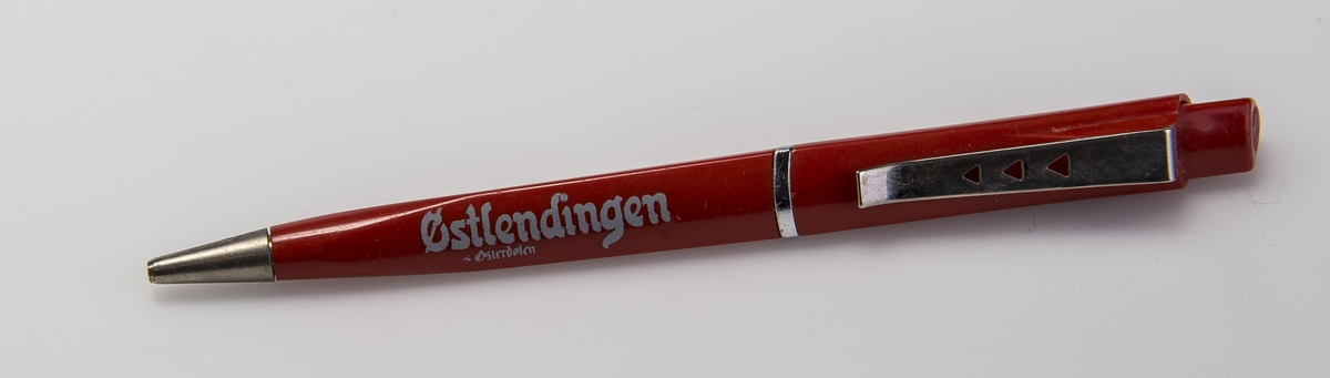 Rød penn med trykknapp. Pennen er formet som en trekant, skråstilte detaljer.