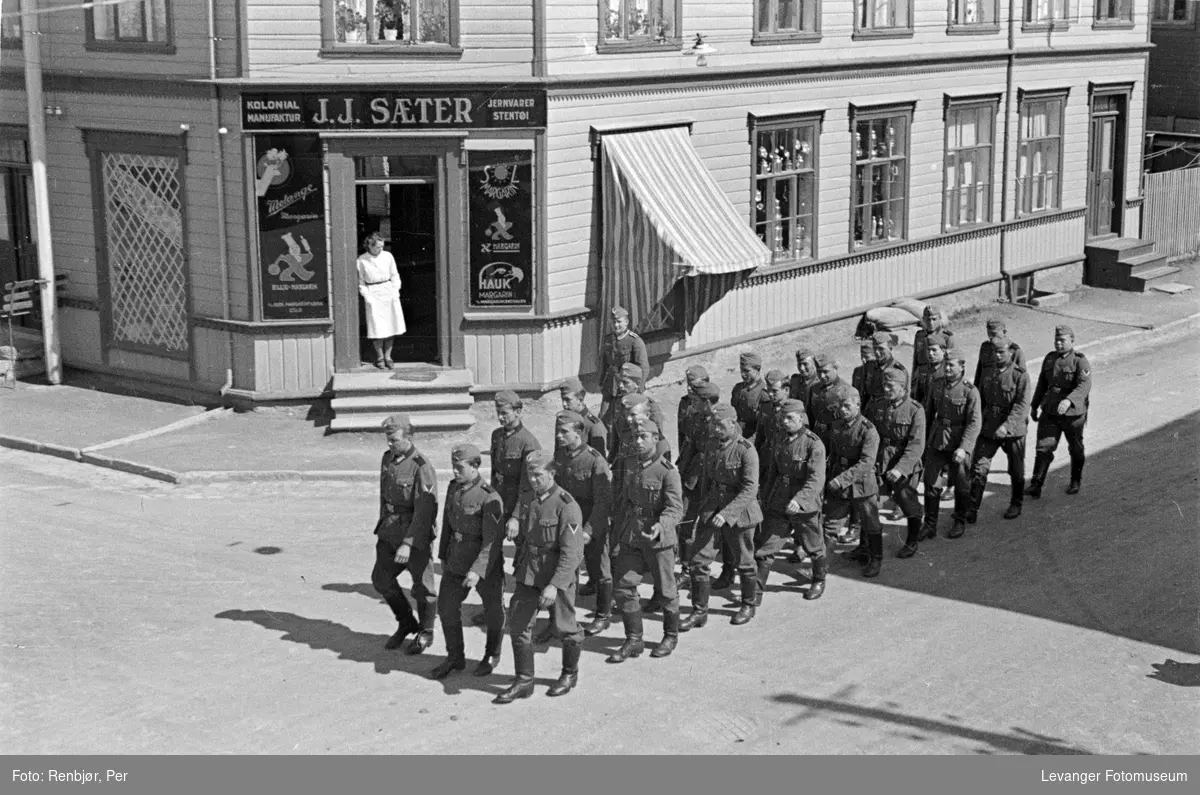 Gatescene tatt fra 2 etasje fra vundu, tyske tropper marsjerer mens en kvinne observerer fra butikken til Sæter.