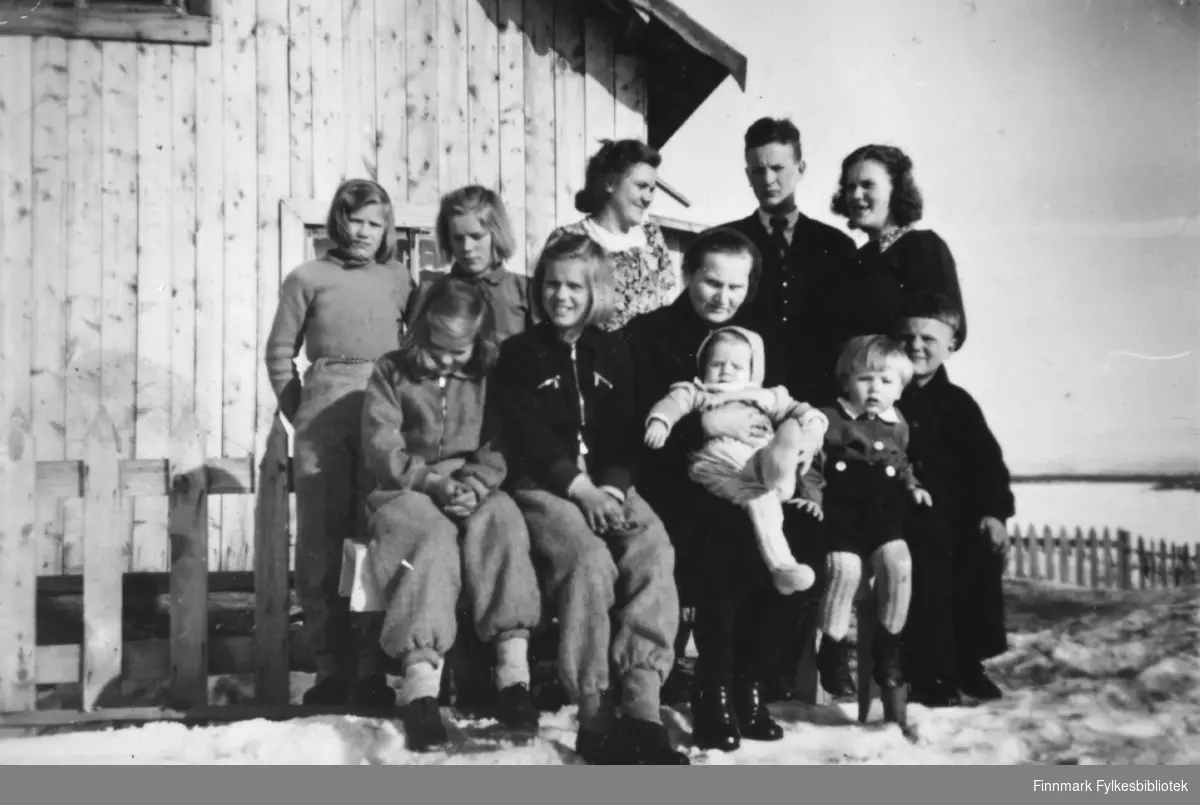 Gruppebilde av familien Stenbakk. Under bildet står det  at "far selv er ikke med" (på bildet). Fotografert på Stensbakk, 1948.