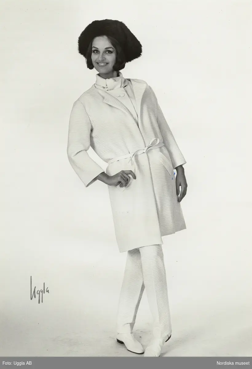 Modell i kappa och byxor i vit jersey och pälshatt. NK:s Franska damskrädderi, original Courrèges.