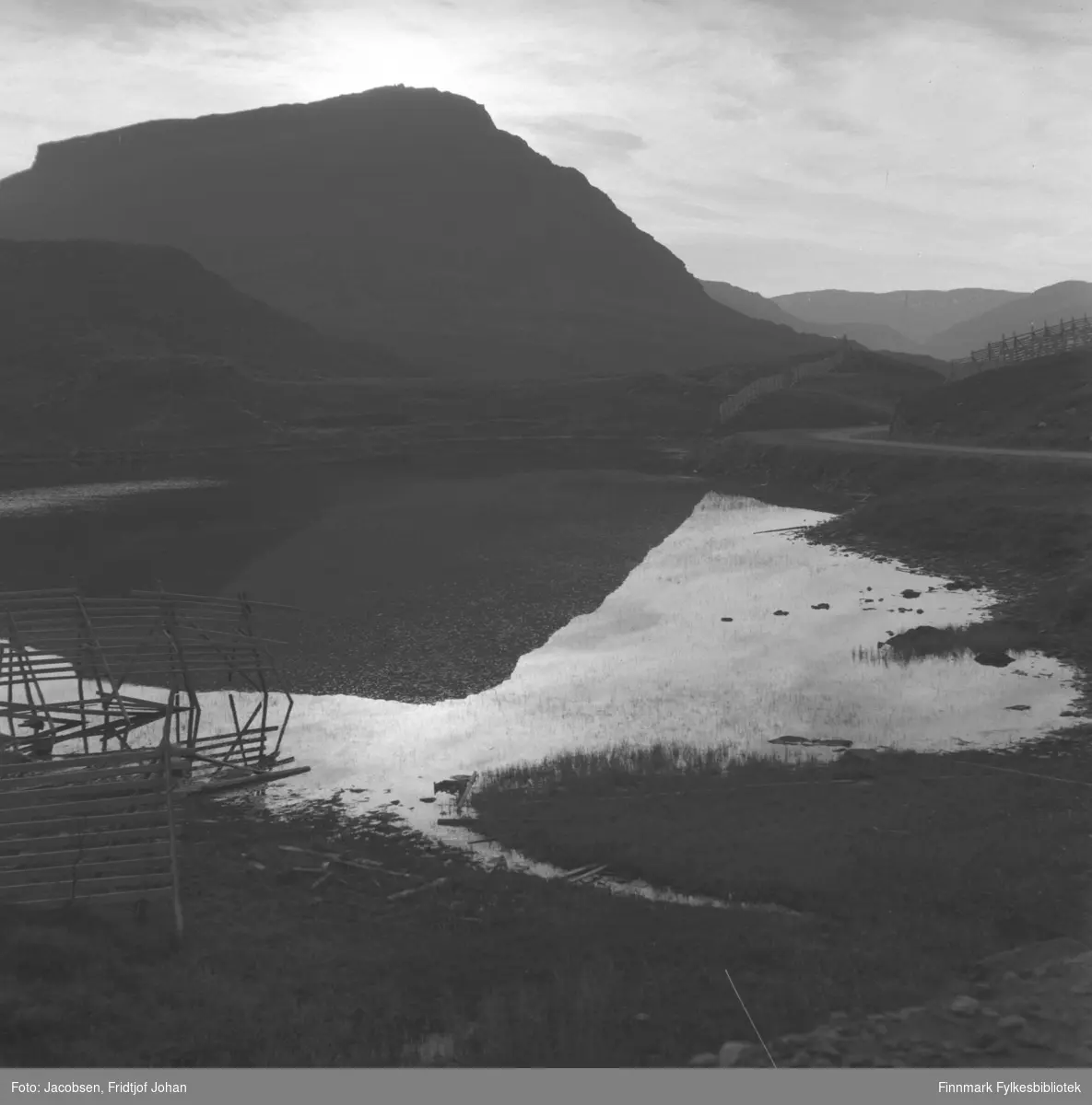Et blikkstille Jansvann med fjellet Tyven i bakgrunnen, fotografert en sommerdag. Rv94 ses til høyre på bildet.