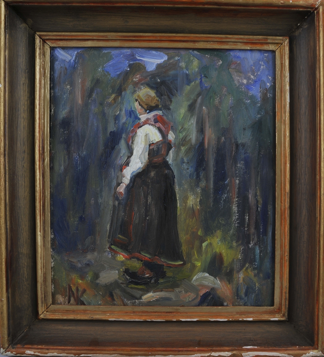 Kvinne i bunad som står i eit skogslandskap, delvis med ryggen mot målaren.