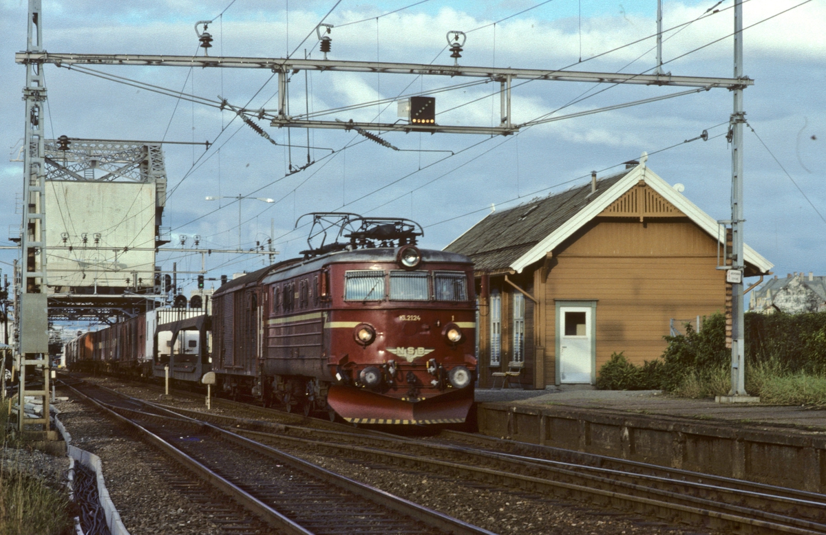NSBs godstog 5712 med elektrisk lokomotiv El 13 2124 kjører ut fra Trondheim over Skansen bru, og forbi Skansen holdeplass.