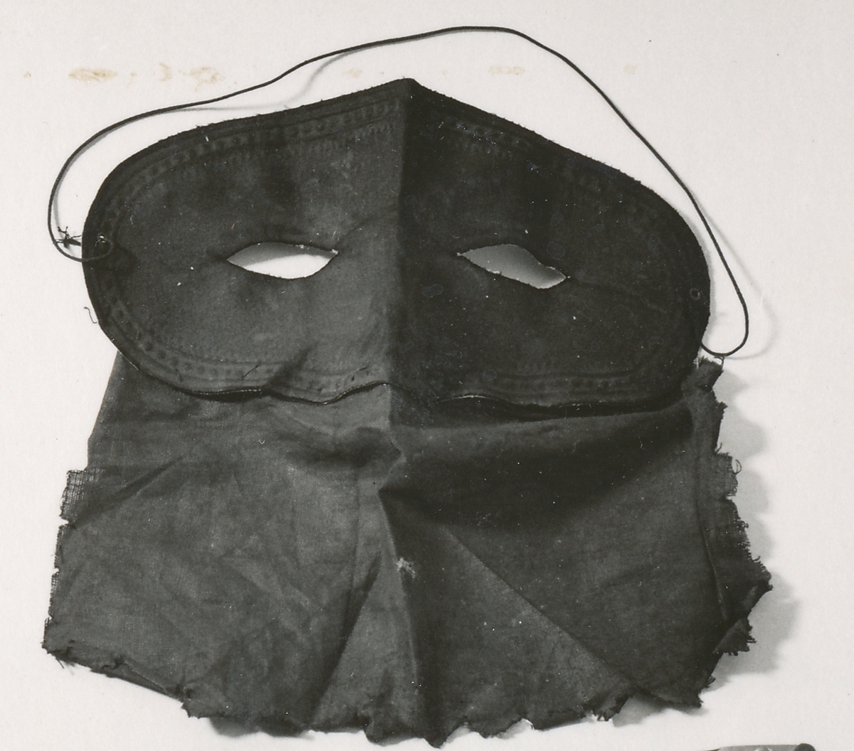 Dominomask av två hopsydda delar.

Den övre, som skulle täcka ögonen är svart på utsidan, på insidan vit. Det undre stycket är brunt och hängde fritt över näsa och mun. Masken togs på med ett tunt resårsnöre bakom nacken. Masken användes vid ett rån mot postkupén på sträckan Simrishamn - Malmö den 18 mars 1907. 
Vaktbetjänten i kupén Johannes Almén blev sårad av tre revolverkulor. Kulorna satt kvar i Alméns huvud i 42 år, ända tills han avled år 1949 i en ålder av 87 år.