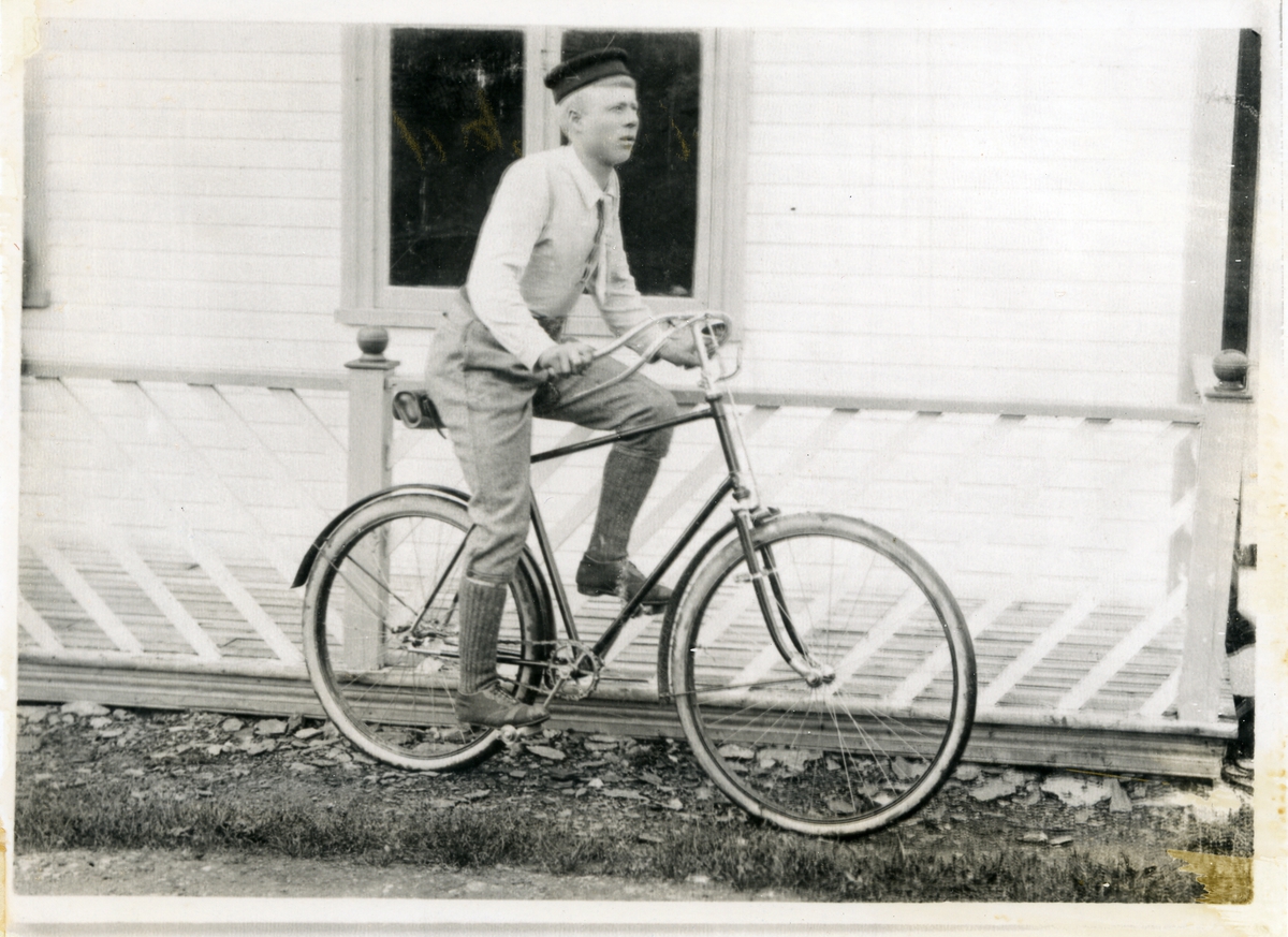 Ung mann på sykkel, fotografert framfor veranda