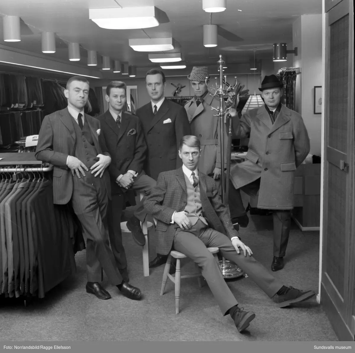 Manliga mannekänger visar kläder inne på Henrix herrekipering för annonsfotografering.