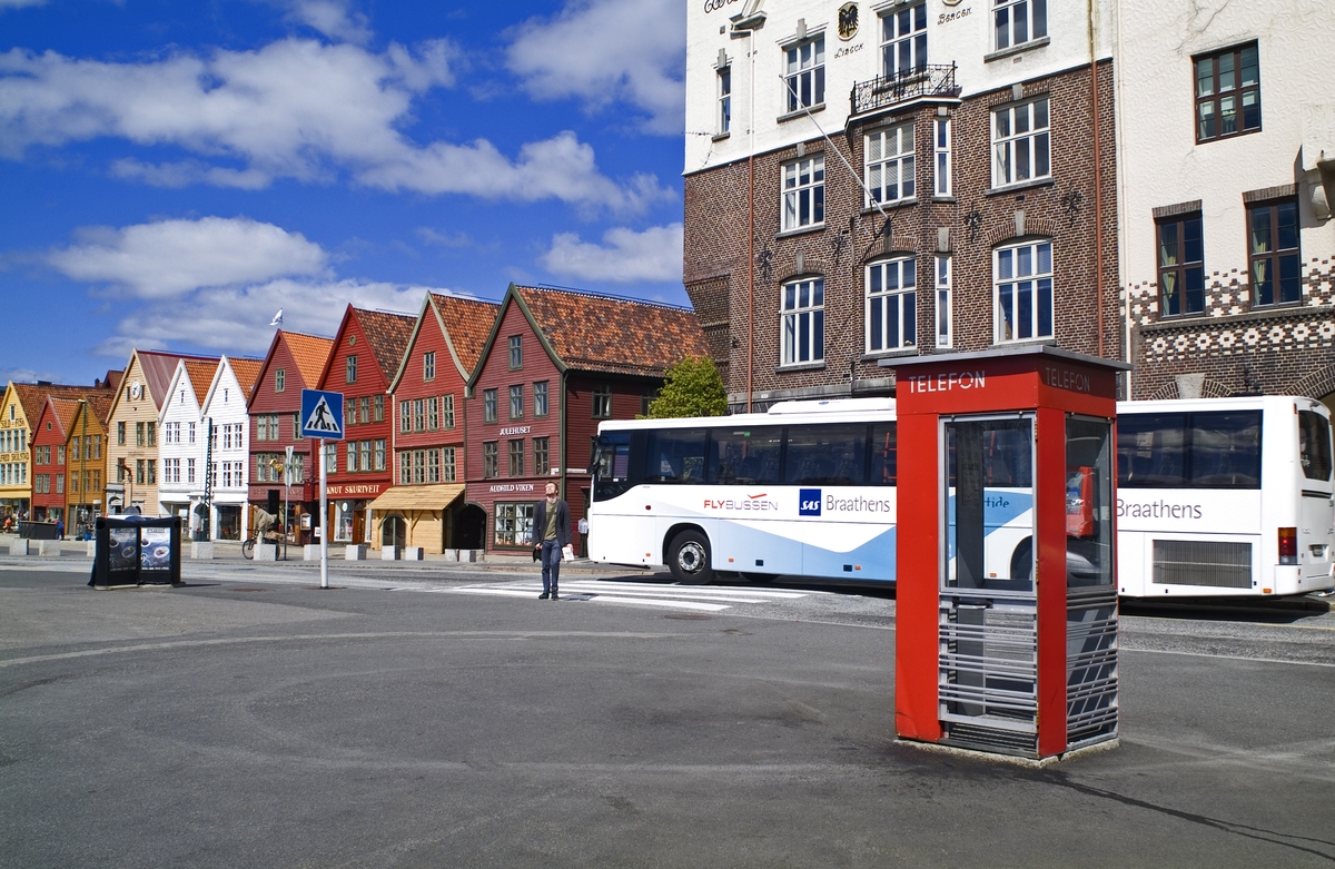 Denne telefonkiosken står på Bryggen i Bergen, og er en av de 100 vernede telefonkioskene i Norge. De røde telefonkioskene ble laget av hovedverkstedet til Telenor (Telegrafverket, Televerket). Målene er så å si uforandret. 
Vi har dessverre ikke hatt kapasitet til å gjøre grundige mål av hver enkelt kiosk som er vernet. 
Blant annet er vekten og høyden på døra endret fra tegningene til hovedverkstedet fra 1933.
Målene fra 1933 var:
Høyde 2500 mm + sokkel på ca 70 mm
Grunnflate 1000x1000 mm.
Vekt 850 kg.
Mange av oss har minner knyttet til den lille røde bygningen. Historien om telefonkiosken er på mange måter historien om oss.  Derfor ble 100 av de røde telefonkioskene rundt om i landet vernet i 1997. Dette er en av dem.
