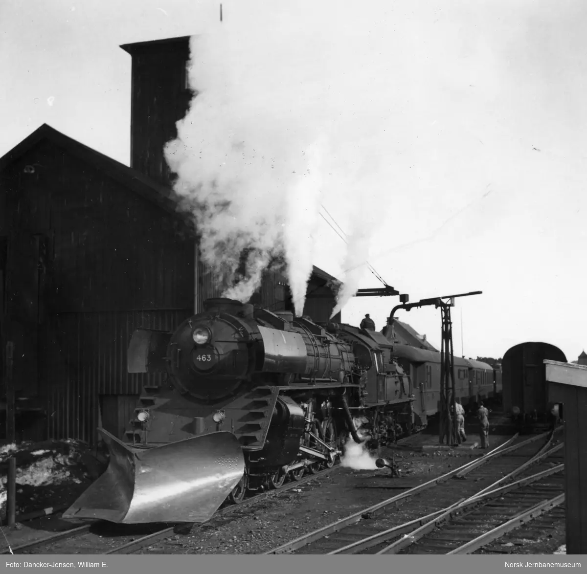 Damplokomotiv type 49a nr. 463 med stor frontplog foran tog 402; vannfylling på Oppdal