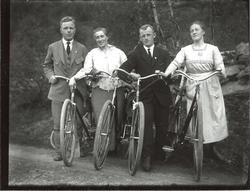 To menn og to kvinner poserer for kamera med hver sin sykkel