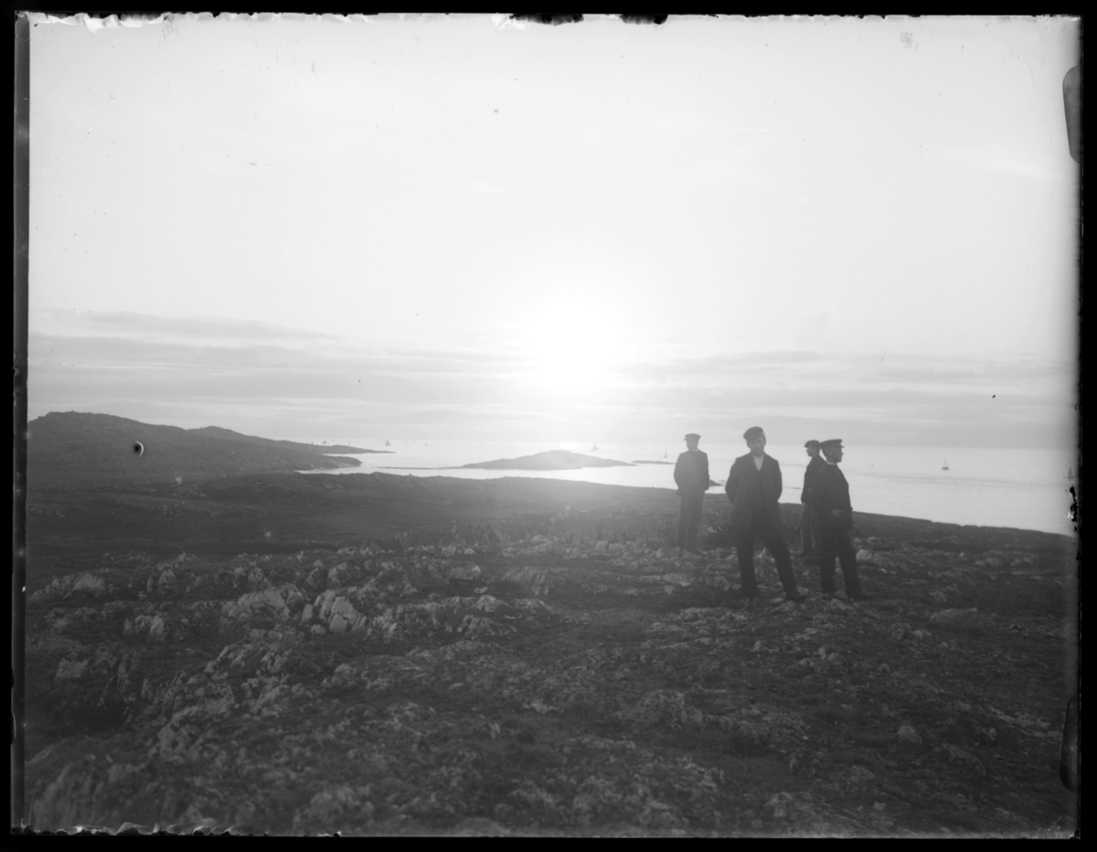 Fire menn er på tur ute i terrenget ved Skagen i Vardø. I bakgrunnen sees Svinøya.