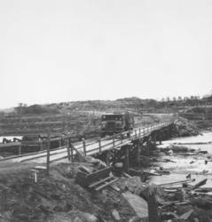 En militær lastebil, Chevrolet, kjører over en bro. Stedet e