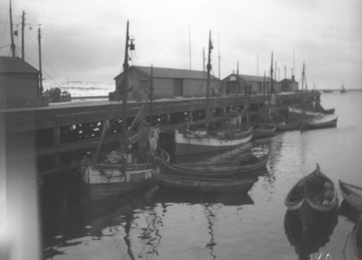 En del fiskebåter ligger langs Dampskipskaia i Vadsø og noen robåter ligger fortøyd litt utpå vannet.
