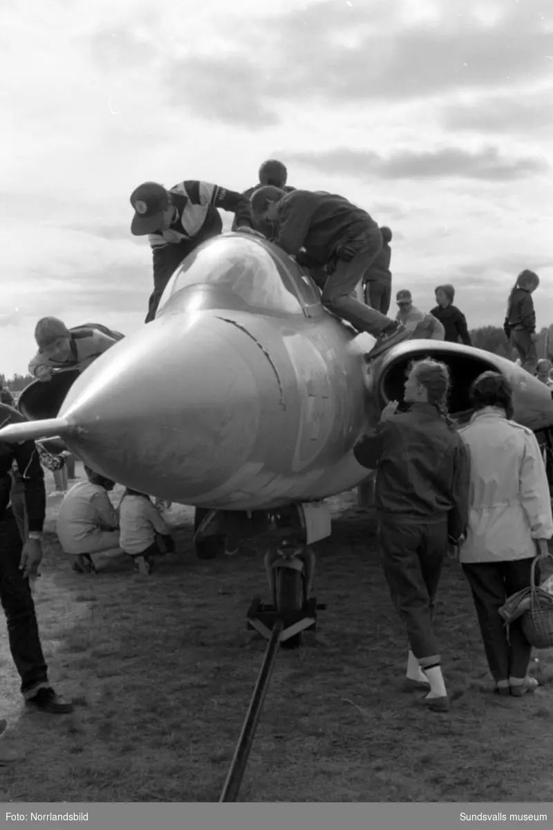Folkfest på Midlanda då 1984 års flygdag arrangerades. Massor av publikbilder med hängflygning, flyguppvisningar, demonstration av flygvapnets ytbärgare med mera. De yngre lockades mest av ett gammalt Drakenplan som stod uppställd för närmare beskådan.