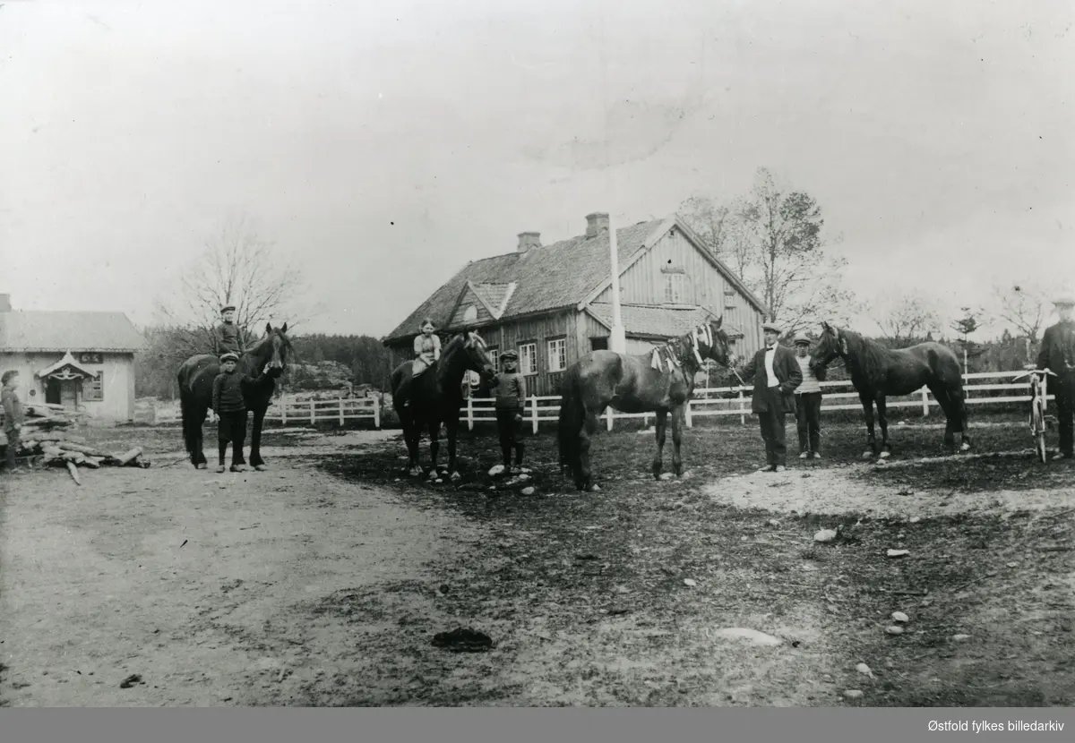 Fra tunet på gården Mysen søndre, Eidsberg ca. 1915-20. Travhester. Sittende på hest nr. 1 fra venstre: Johan Jensen, broren Olaf Jensen holder hesten. Sittende på hest nr. 2 fra venstre: Dagny Belsby (hest "Tandberg"), Asbjørn Belsby holder hesten. Hest nr. 3 fra v.: "Bravur" (m. mange sløyfer), blir holdt av Johannes Mysen.