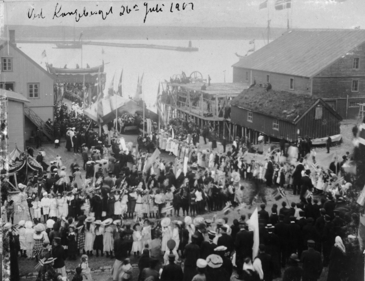 På bildet er det skrevet "Ved Kongebesøget 26. juli 1907." En Nordlandsbåt utgjorde æresportalen med to levende fiskere i båten.  Det var de to mennene med det lengste skjegget som ble valgt ut,  den ene var fra Hamningberg og den andre var fra Makkaur.