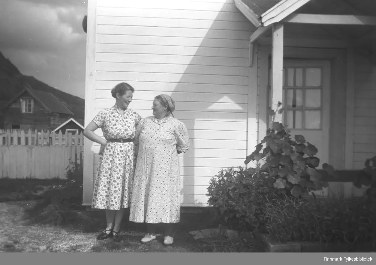 Fra venstre: Karen og Kathinka Mikkola, fotografert foran inngangen til våningshuset på gården Mikkelsnes i Neiden. Foran trappa ser vi frodige sommerblomster