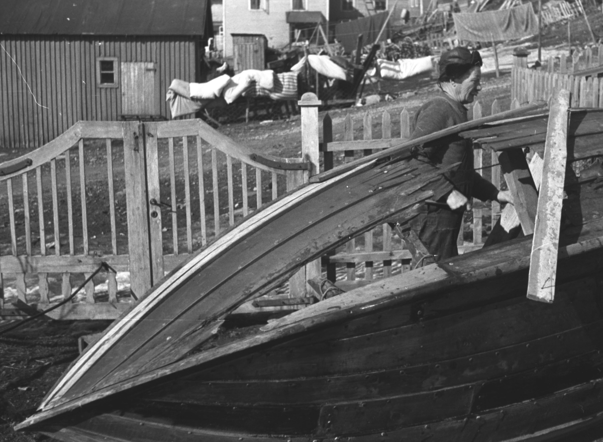 En robåt har fått sprengt et hull i siden av en tysk håndgranat.. Alfred Amundsen er i gang med å fikse båten i hagen hos familien Hauge i Nyborgveien.