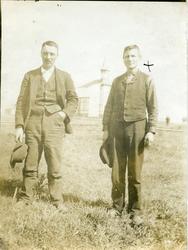 To menn avbildet foran en kirke. Mennene er iført hverdagskl