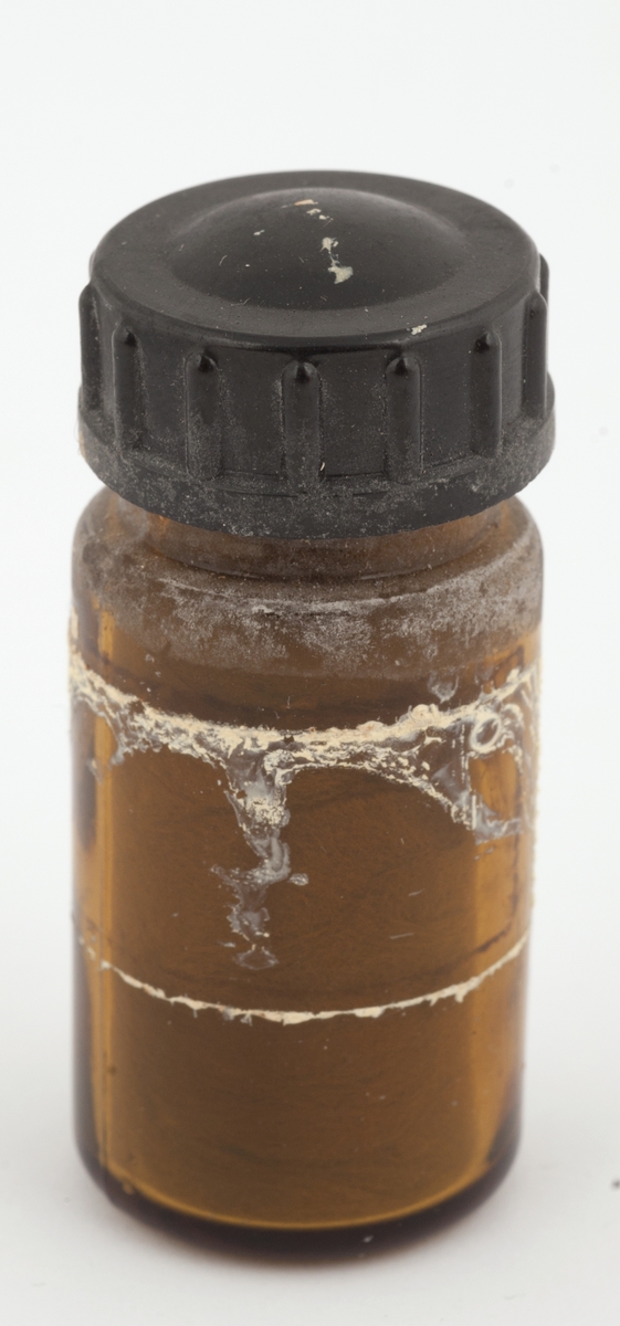 Styptisk bomull i medisinglass med skrulokk. 
Glasset har rester etter lim for etikett. Pålimt streifetikett med nr. 090  og 11 2  63