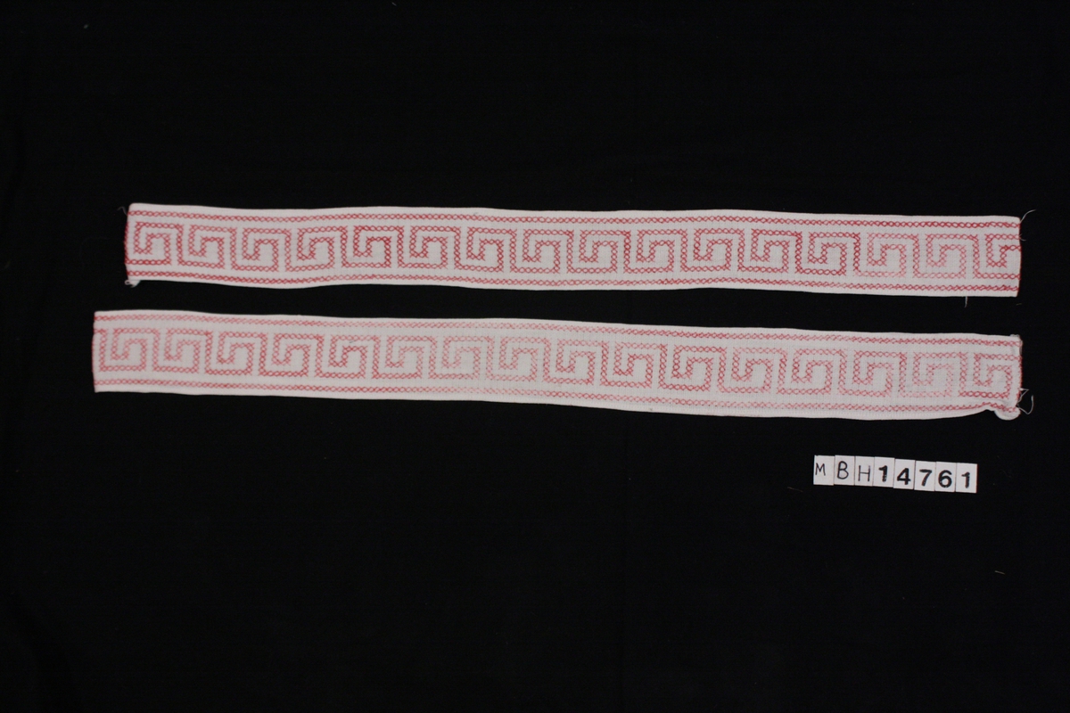 2 stykken broderte tekstiler, trolig bukseseler. Hvit bomull, med brodert mønster i korsting med rosa bomullstråd. Stilistisk mønster. Påsydd hvitt bomullsfor på den ene siden.