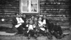 Store og små samlet utenfor et trehus på Elvebakken. De sitt