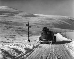 Fotografi av en VW-bil på en snødekt vei på vidda..