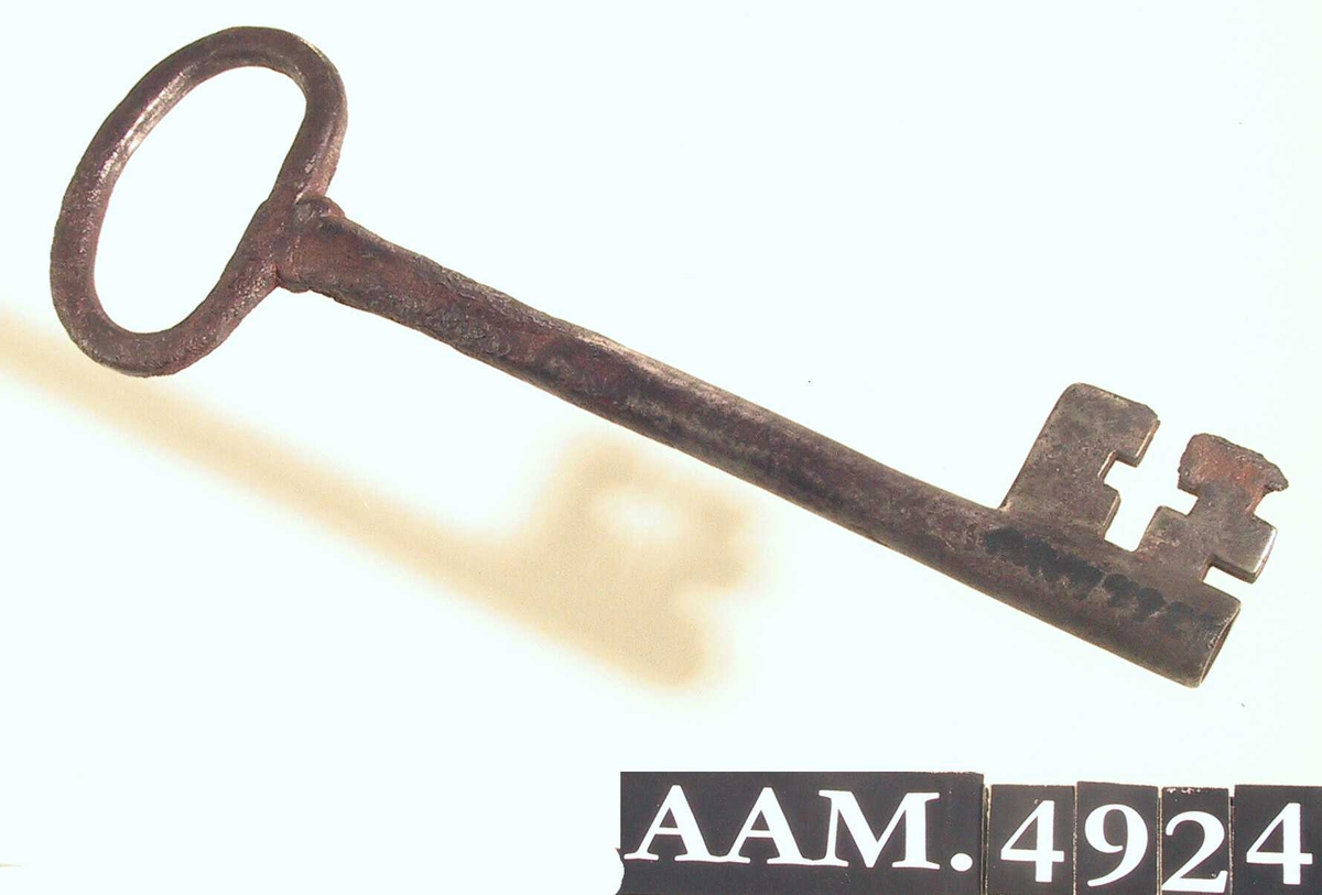 Nøkkel,  ant. til hoveddør. Jern.  Rett, hul pipe, ovalt håndtak, plate med korsformet åpning.  Innk. 28/5 1965, lå på bunnen av døpefont Eide, AAM.4909.