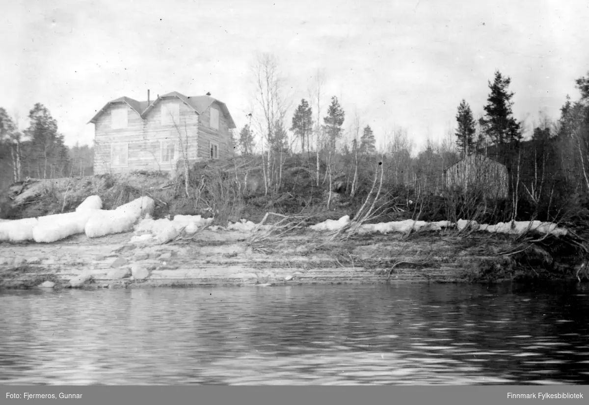 Et stort hus med valmet tak bygd på en liten høyde rett ovenfor vannkanten. Stedet er ukjent, men bildet er tatt i 1947.