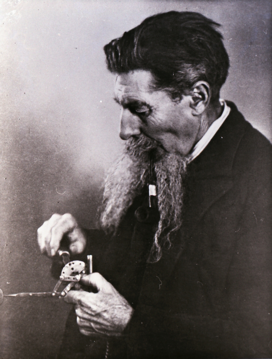 Portrett av en mann som finstiller et instrument/ apparat.