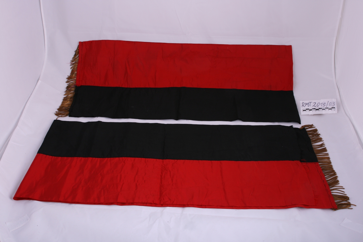 Stort bånd i rødt og svart, delt i to deler, har trolig originalt vært et langt bånd.