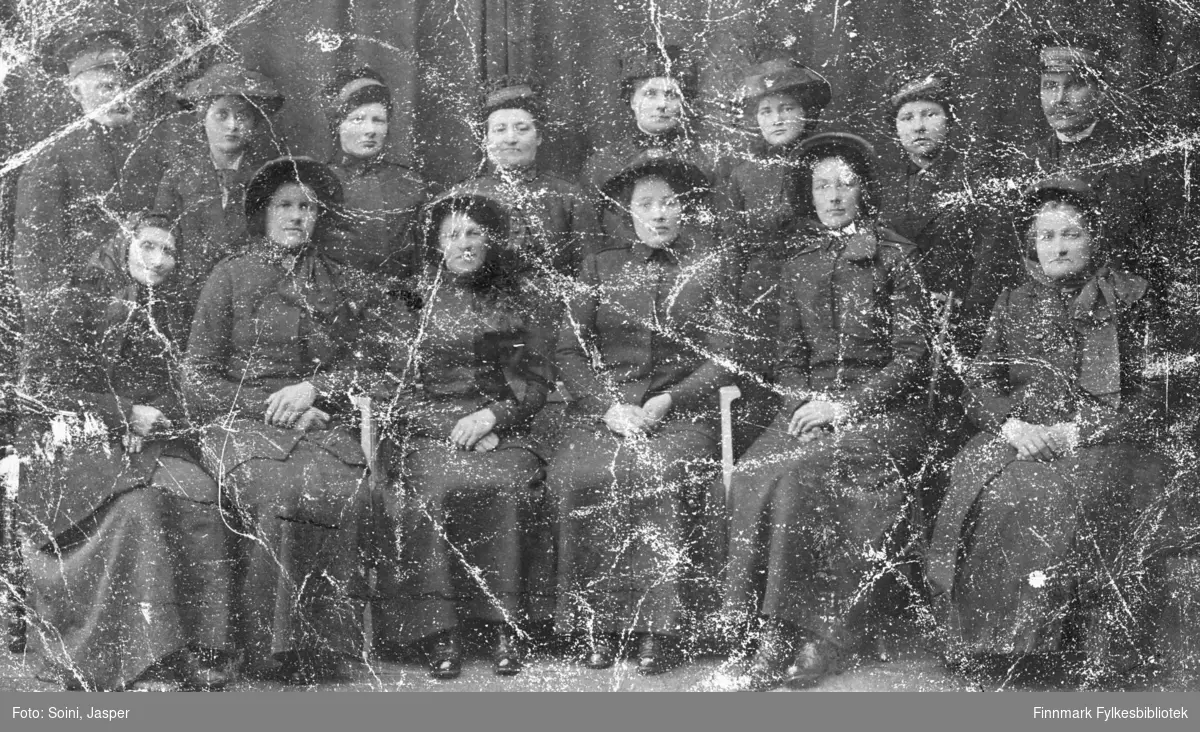 Frelsesarmeen fotografert hos J.Soini i Vadsø. 12 kvinner og to menn, seks av dem sittende i første rekke og seks stående bak. Dagny Rebekka Pedersen (g. Mietinen) er den tredje fra høyre bakerste rekke. Alle er kledd i uniform.