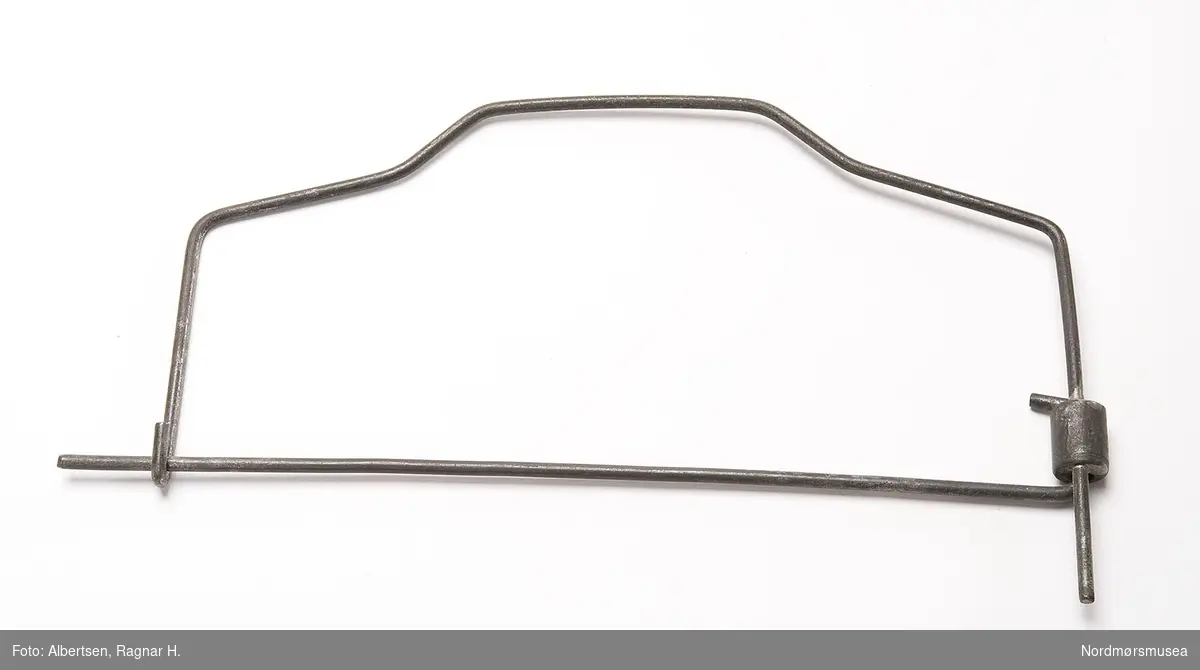BESKR: Svingleddet er et sylindrisk lodd med to gjennomgående hull. I det ene hullet er en ståltråd loddet fast, i det andre går en ståltråd bøyd 180 grader. Denne tråden er "bunnen" i ramma og er hektet i en krok på motsatt side.