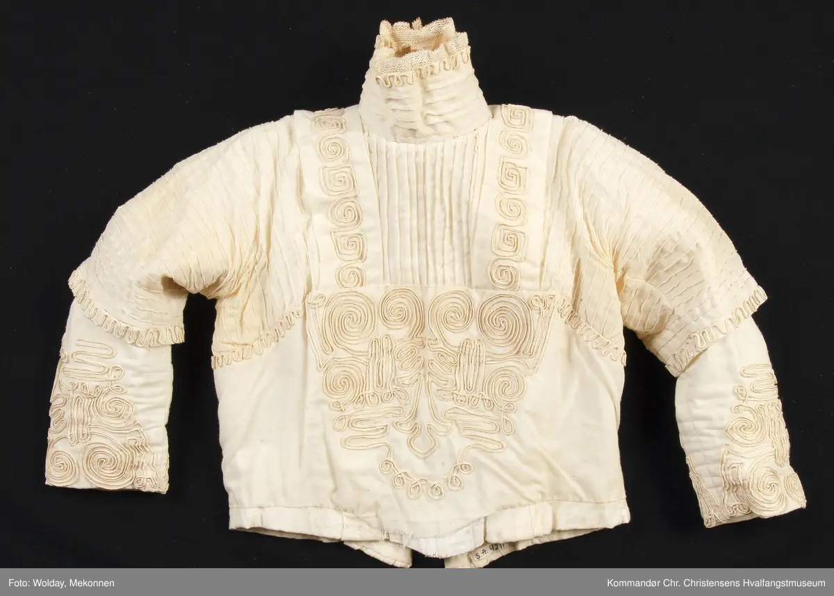 Teknikk: Håndarbeid. Sydd både for hånd og på maskin Høy krave av bomullsblonde. 3/4 lange ermer m/albulange overermer
