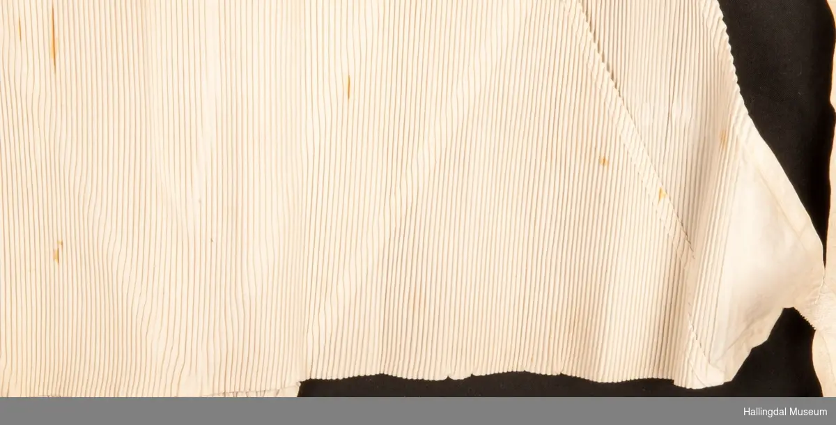 firkantet tøystykke som er brettet 2 ganger (4 flater), stivet og plissert