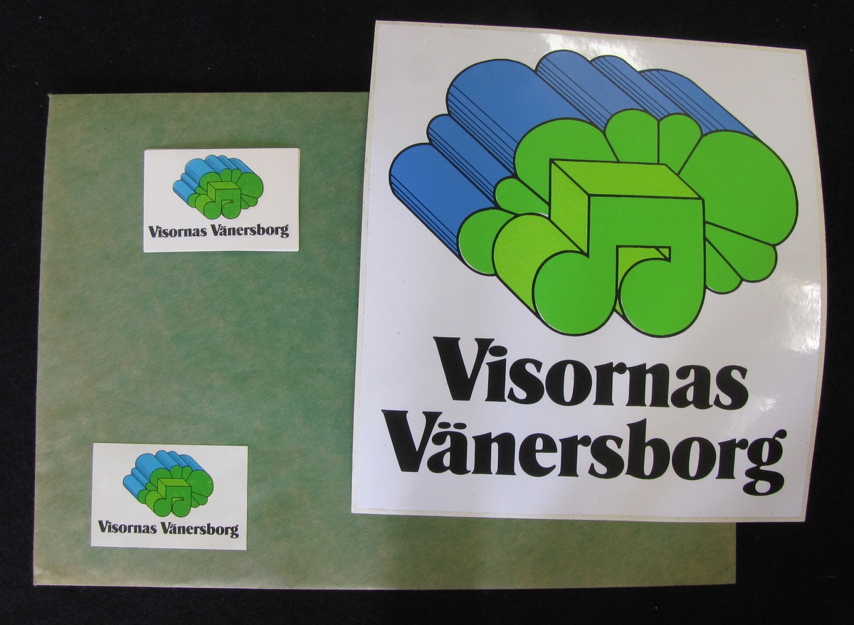 Klistermärken med en logga med Visornas Vänersborg som kommunen Vänersborg ville marknadsföra sig som 1970. Logotypen är i grönt och blått. Et sort klistermärke och sju små ligger i ett grönt kuvert.

Bilaga finns.
