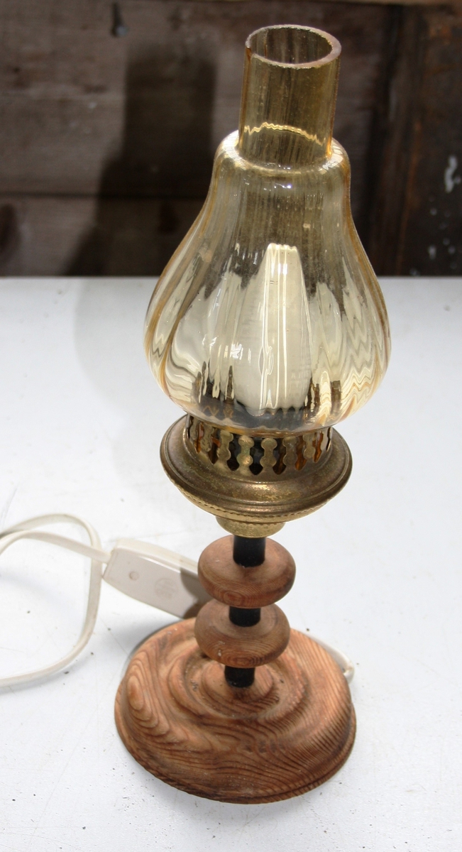 Liten elektrisk bordlampe med rund fot og gjennomsiktig laus glaskuppel med messingfarga blikkhaldar