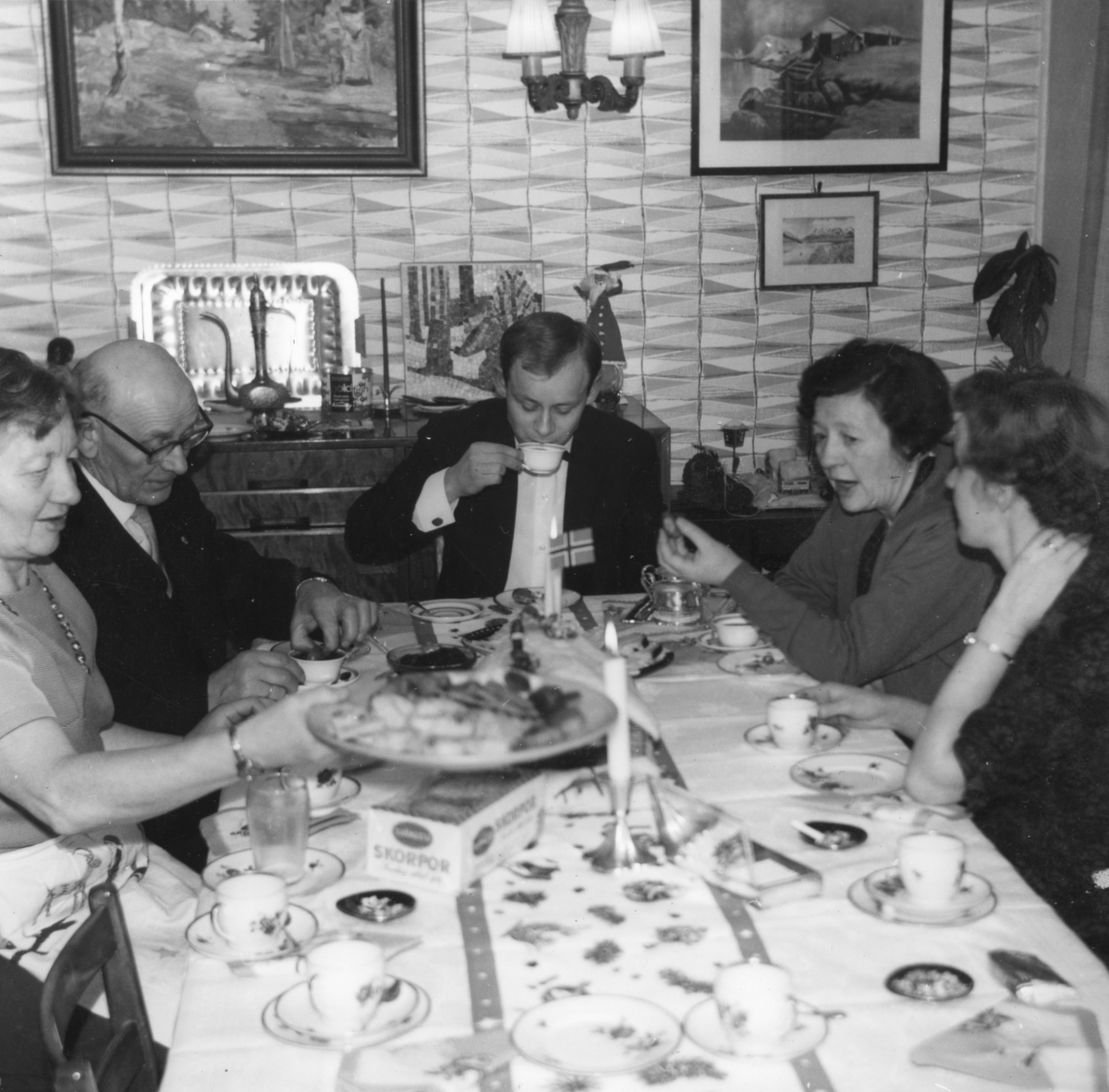 Kvinner og menn rundt bord med kaffe og kaker.