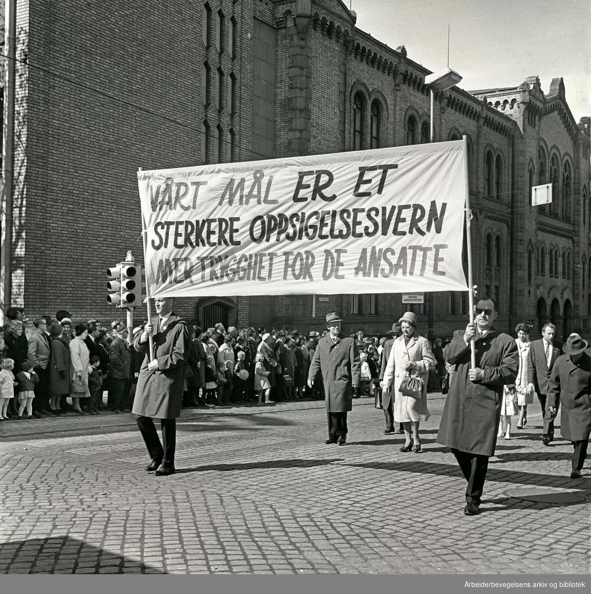 1. mai 1964 i Oslo.Demonstrasjonstoget i Karl Johans gate.Parole: Vårt mål er et sterkere oppsigelsesvern.mer trygghet for de ansatte