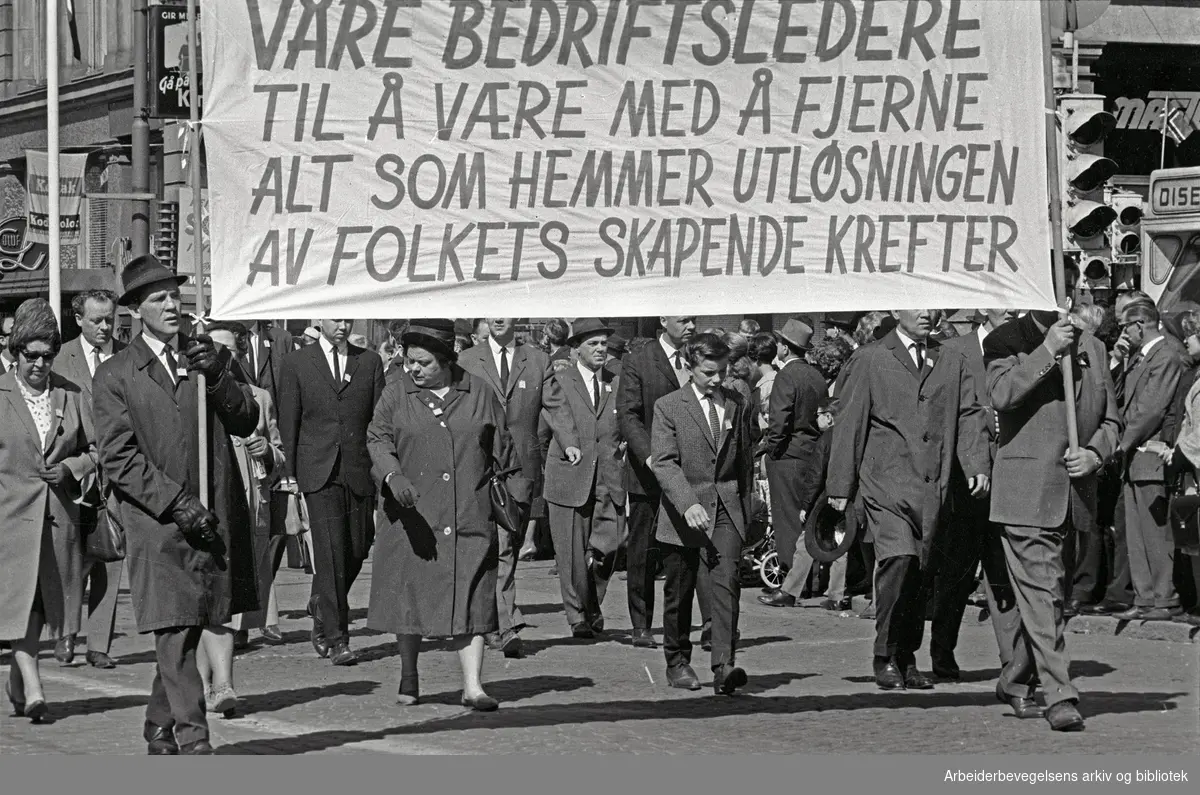 1. mai 1965 i Oslo.Demonstrasjonstoget i Karl Johans gate.Parole: Få våre bedriftsledere til å være med å fjerne alt som hemmer utløsningen av folkets skapende krefter