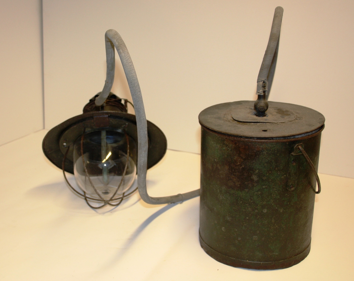 Gjenstanden består av to huvedobjekt, ein rund lampe med glas og ein rund tank med blikkbeholder inni til karbid.
Ein gummislange skal gå mellom tank og lampe.