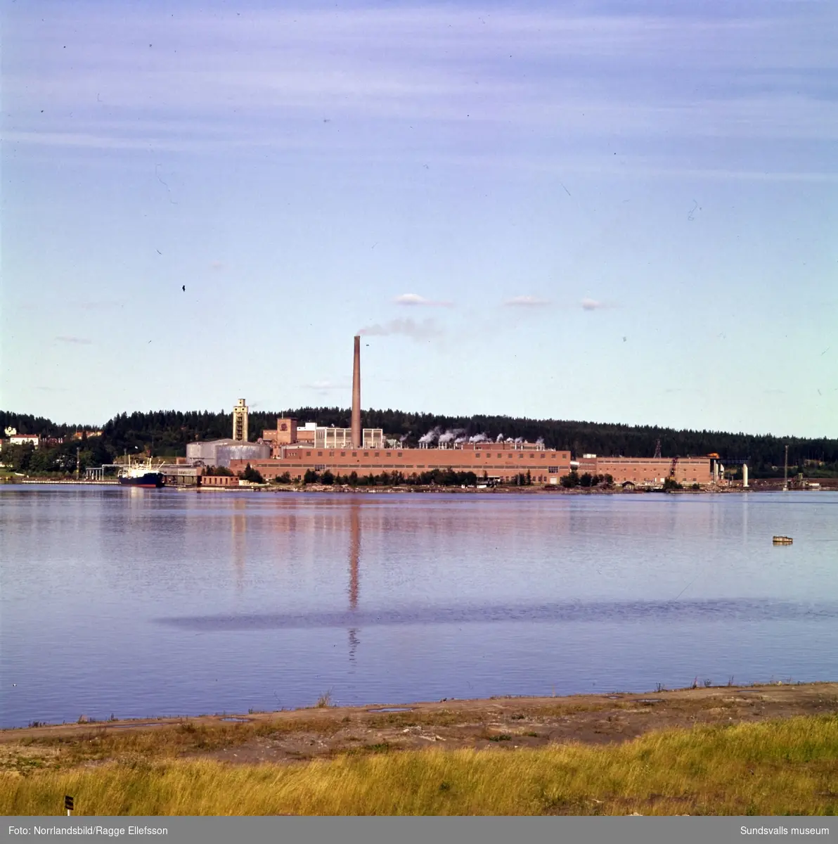 Ortvikens pappersfabrik fotograferad från andra sidan vattnet.