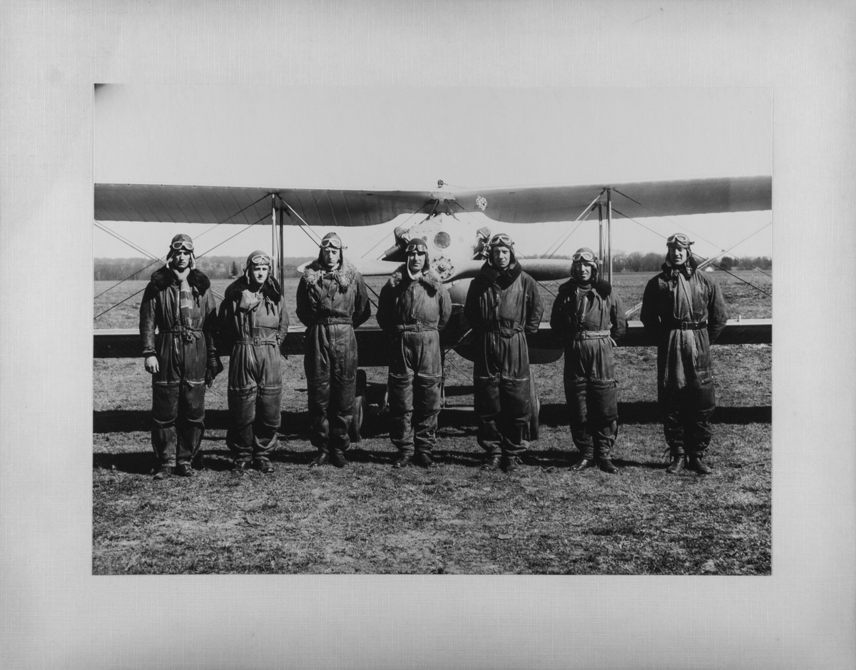 Deltagare i jaktkursen på F 5 1929-1930. Grupporträtt av sju flygförare framför flygplan.
