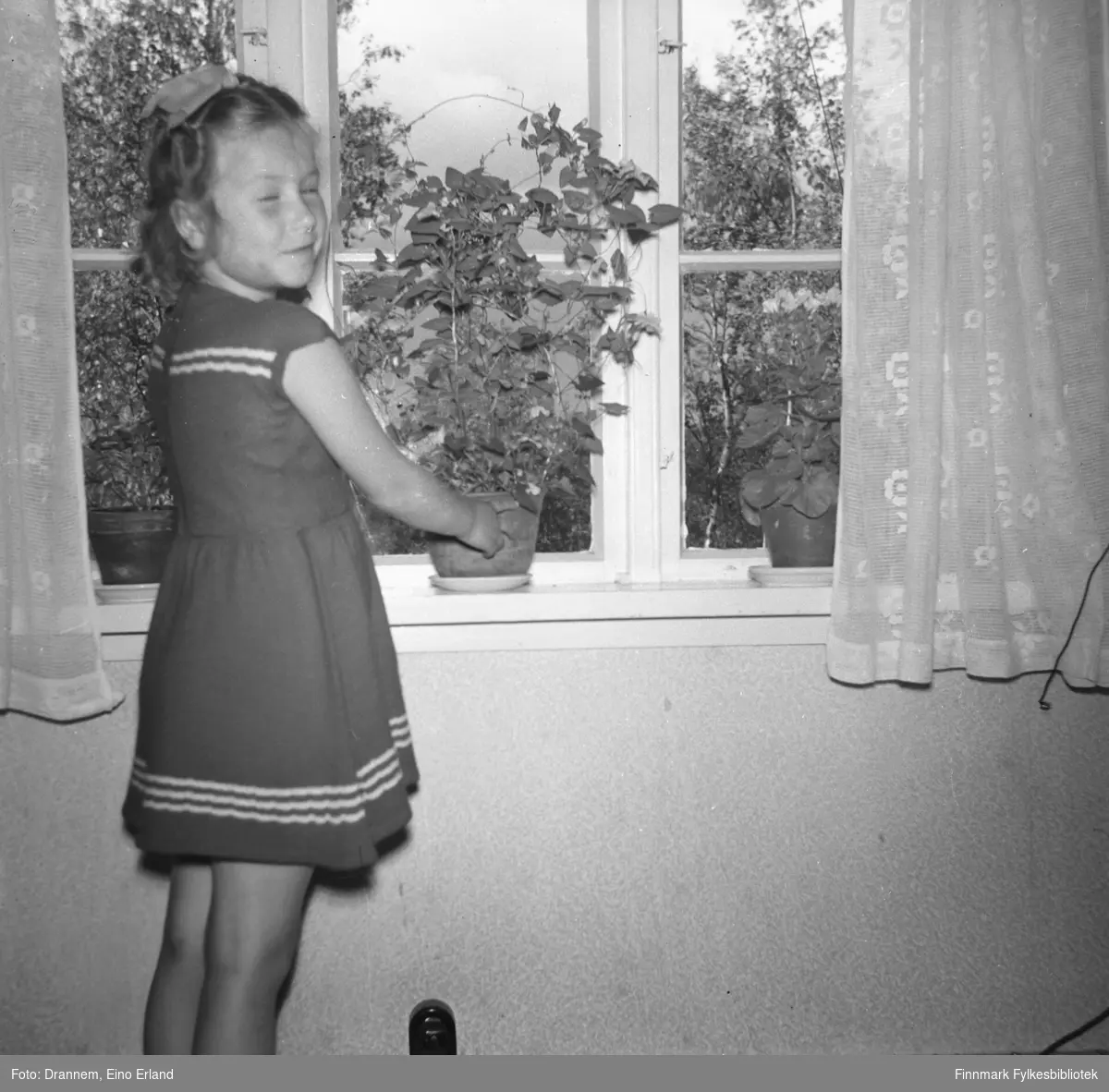 Turid Lillian, fotografert foran vinduet. Man ser stueplanter i vindusposten