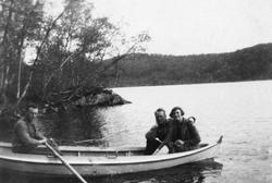 To menn og en kvinne i en robåt.