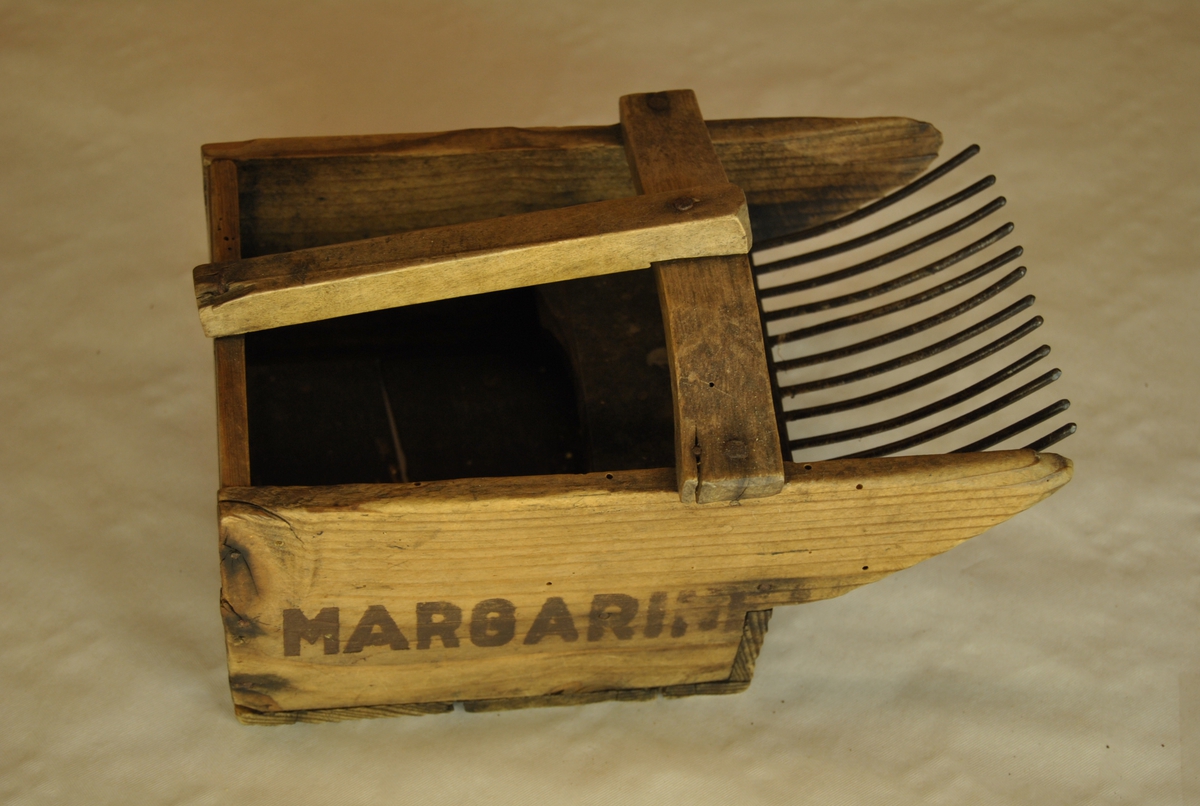 Bærplukker i tre med jerntenner. Med håndtak. Lagd av margarinkasse fra Aalesund.