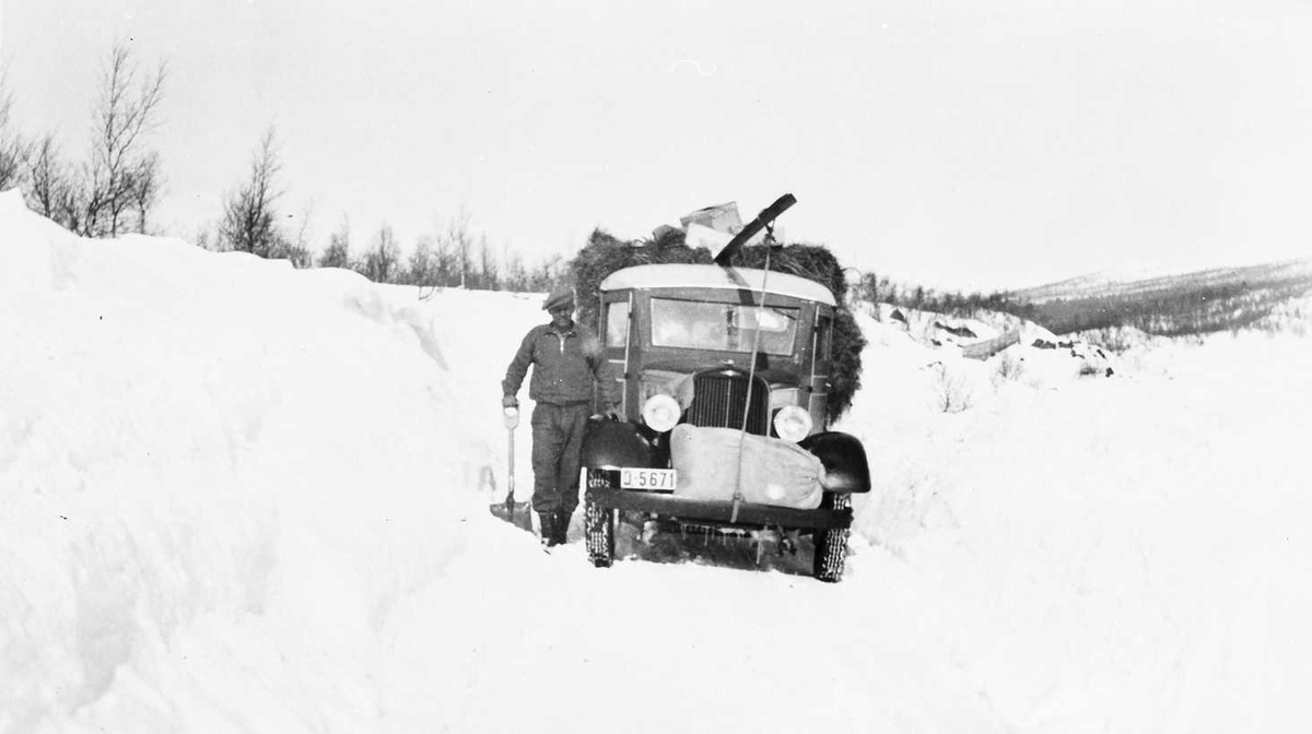 Mann med lastebil i mye snø, lass med høy
