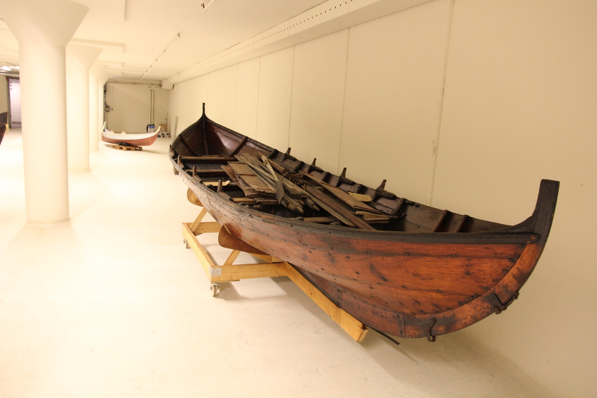 Tjæret båt for fire roere. Antas å tilhøre båten: 1 par årer, gråmalte, mrk. M. Skaalvik, NSM.4245 (stokkebåt?), og 6 skvettbord (antas å kunne tilhøre denne båten iflg. Arne Emil Christensen, båtekspert ved Sjøfartsmuseet 2009. I båten lå flaske (samme mrk., samme reg.nr.)